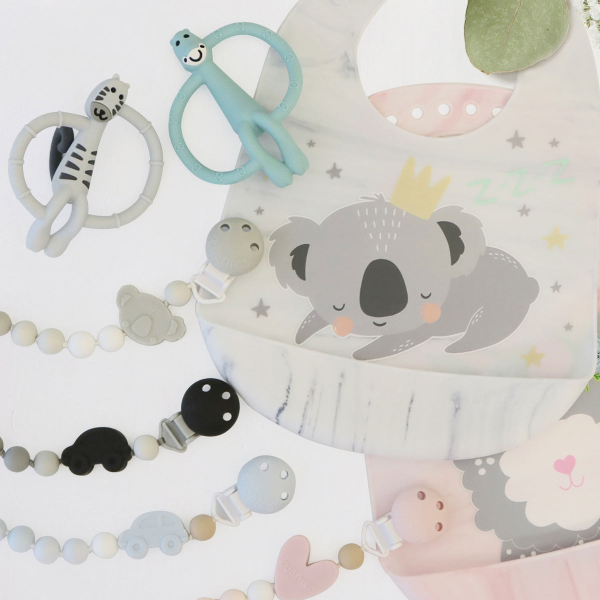 silicone bibs with pacifier clips and teething toys on table