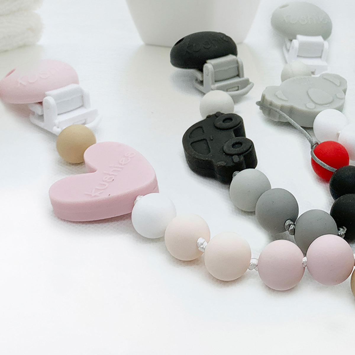 pink heart black car and grey koala pacifier clips on table