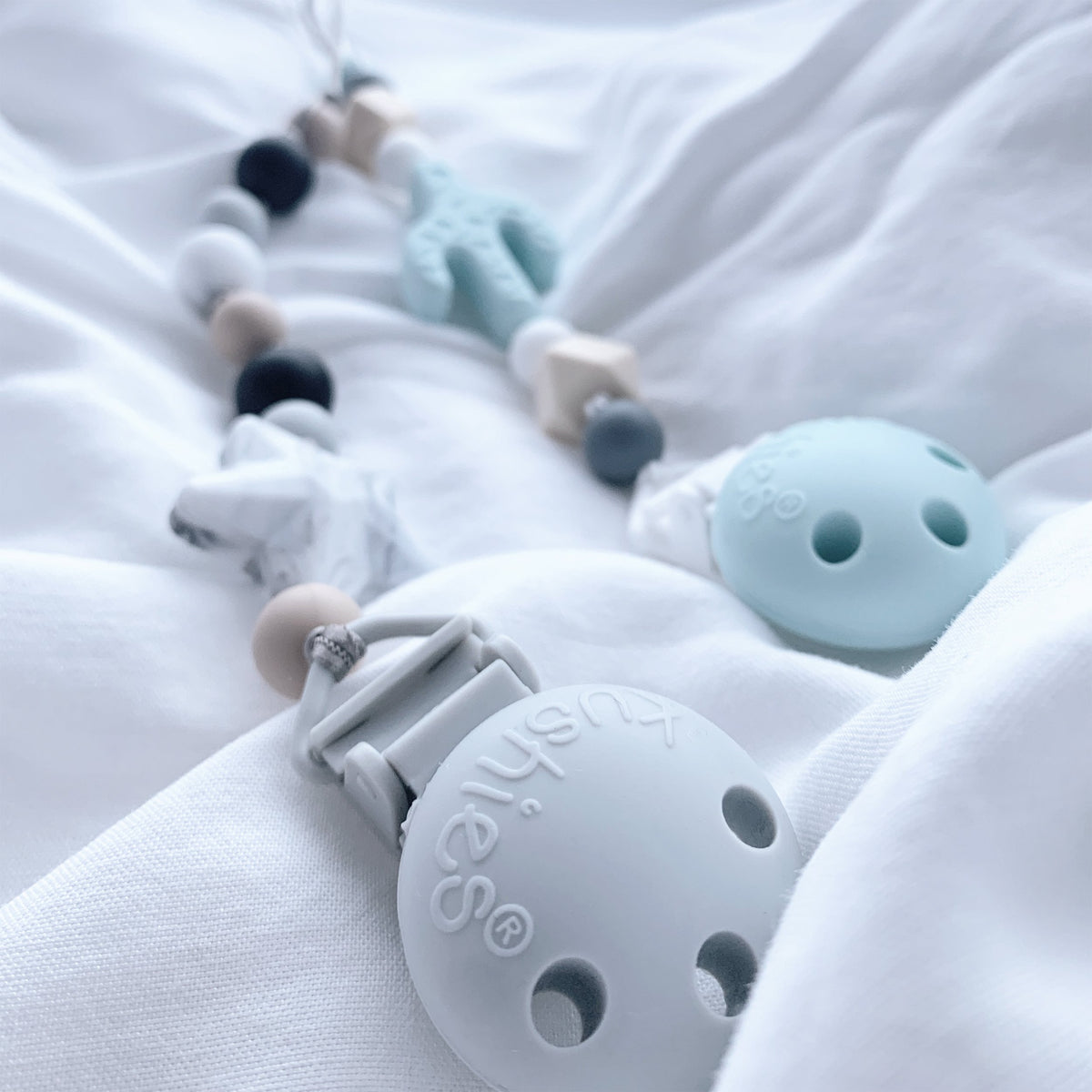two silicone pacifier clips on bedding